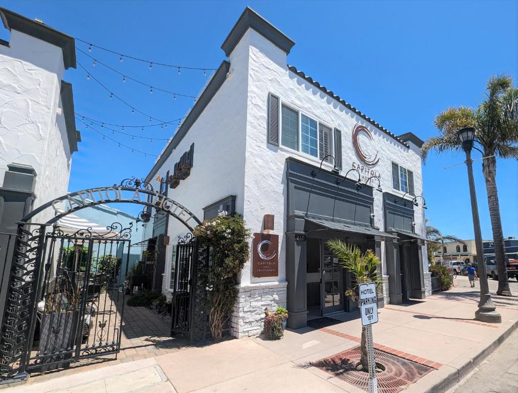 a white building with a gate on a street at Capitola Hotel in Capitola