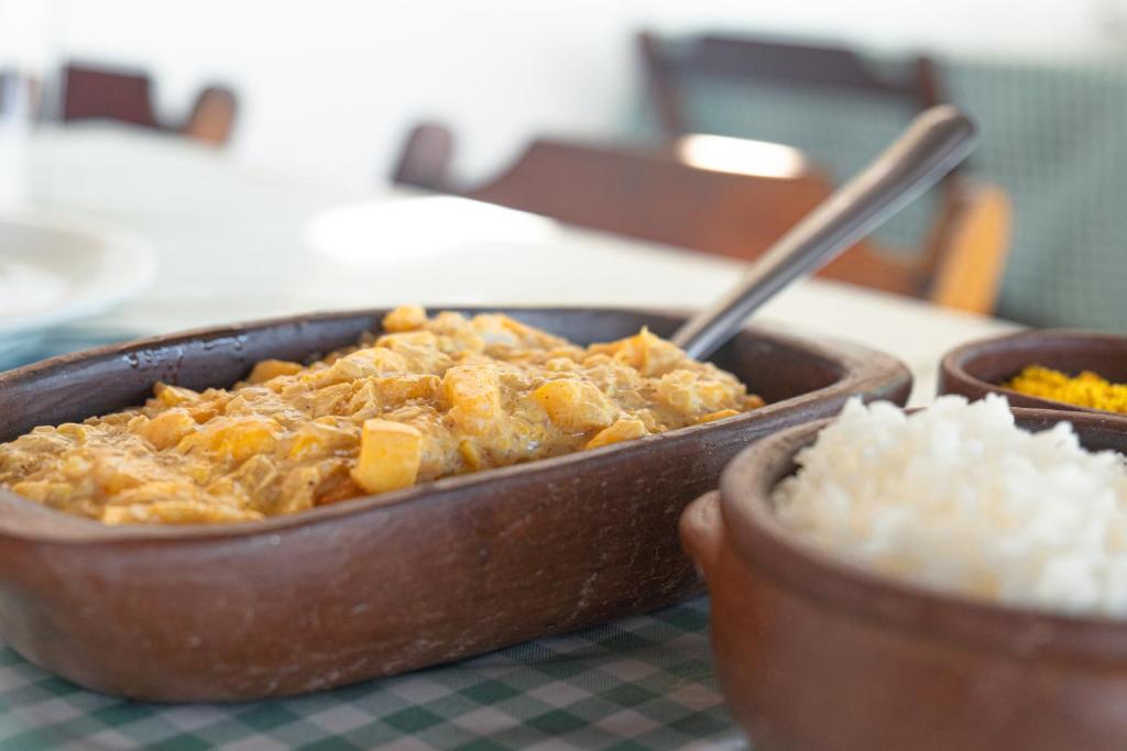 a casserole dish of food on a table with rice at Pousada Recanto da Mãezinha in Beberibe