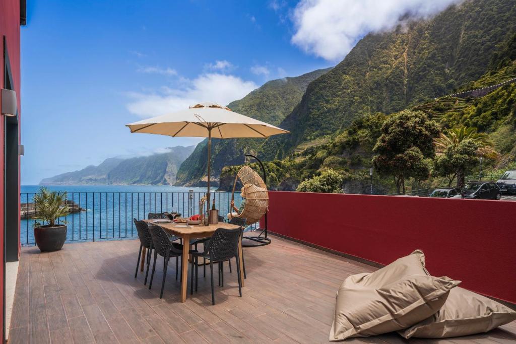 uma mesa com um guarda-chuva numa varanda com vista para o oceano em Holiday home by the sea Pipas do Avô - Seixal em Porto Moniz