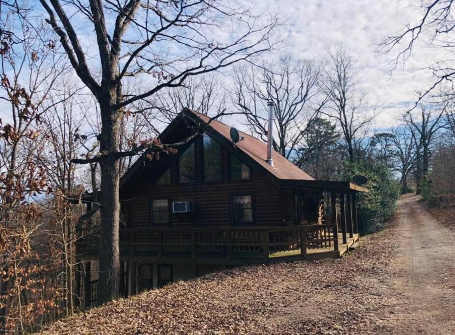 a log cabin on a hill next to a dirt road at The Loft at Bear Mountain log cabins in Eureka Springs