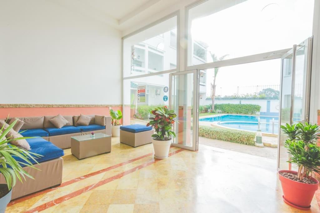 uma sala de estar com um sofá azul e algumas plantas em lovely 2 bedroom vacation home with pool/beach em Skhirat
