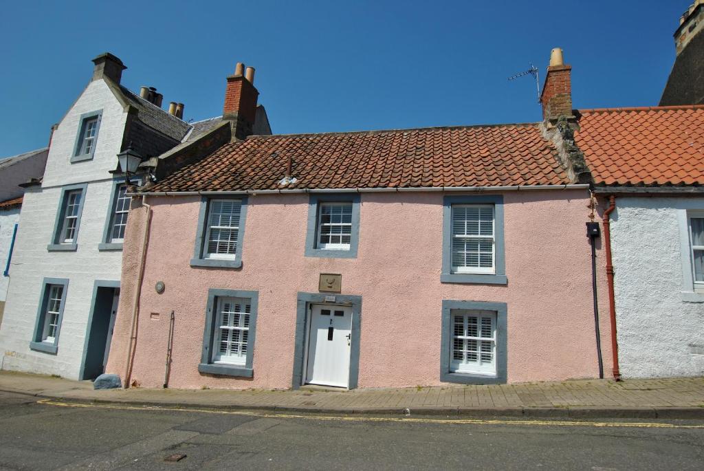 a pink house with a red roof on a street at The Cottage by the Harbour St Monans in Saint Monance