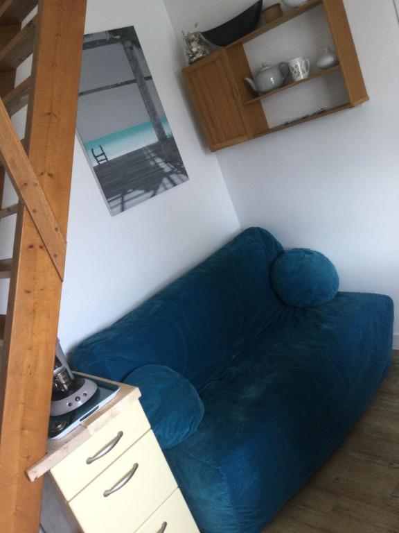 a blue couch in a living room with a ladder at Baie de Somme, Quend-Plage, 50m de plage, appart 4 a 6 personnes in Quend