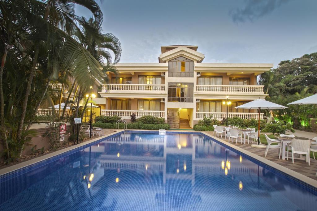 a hotel with a swimming pool in front of a building at De Mandarin Beach Resort Suites & Villas, Candolim in Candolim