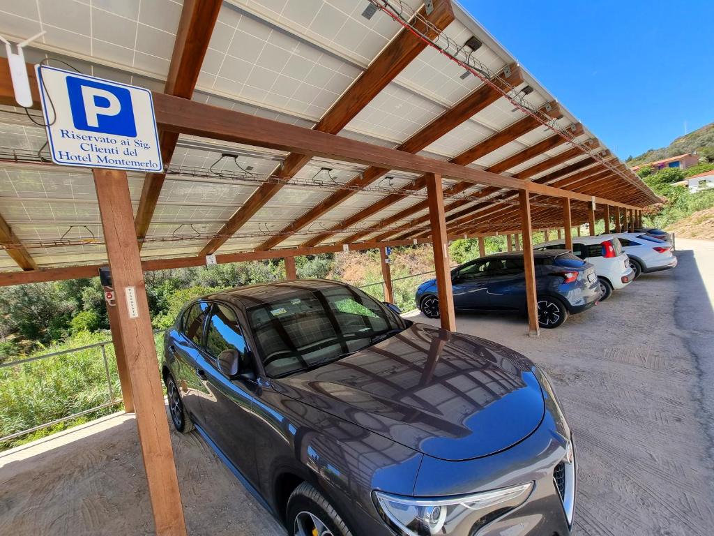 a carport with a parking lot with cars parked under a roof at Eco Hotel Montemerlo in Fetovaia