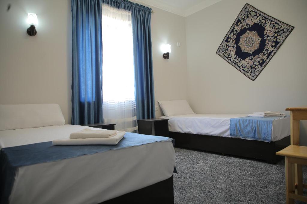 a hotel room with two beds and a window at Rasul-Nazar in Khiva