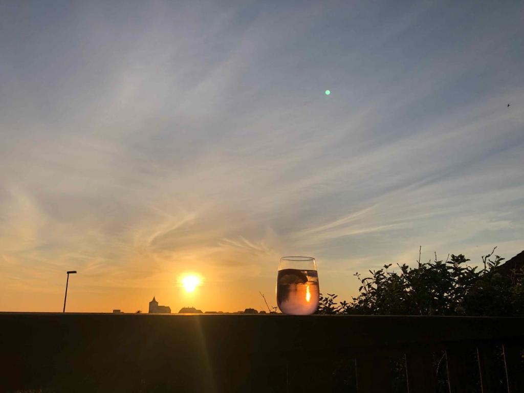 een glas op een richel met de zonsondergang op de achtergrond bij Wooden House With A View Of The North Sea in Lemvig