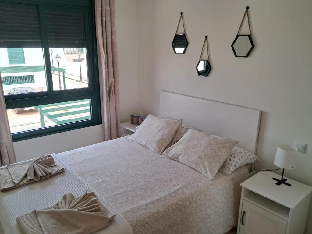 sypialnia z białym łóżkiem i oknem w obiekcie Casita A Pitisa w mieście Playa Blanca
