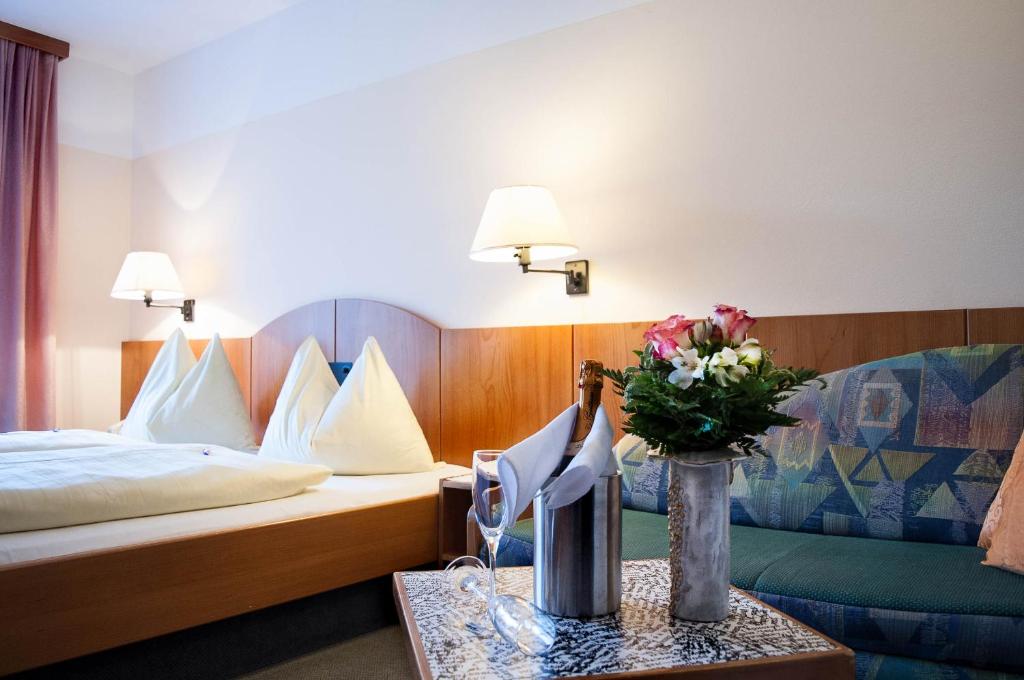 um quarto de hotel com uma cama e uma mesa com flores em Hotel Edlingerwirt - Sauna & Golfsimulator inklusive em Spittal an der Drau