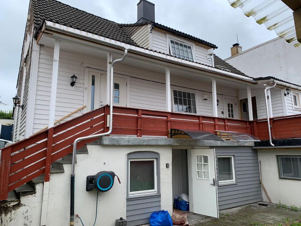 a white house with a red railing on the porch at Central and Large cosey apartment in Stavanger