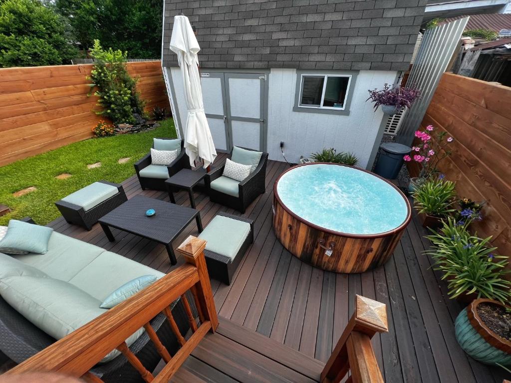 una terrazza in legno con vasca idromassaggio e sedie. di Luxury Historic Shotgun Home in Lower Garden District a New Orleans