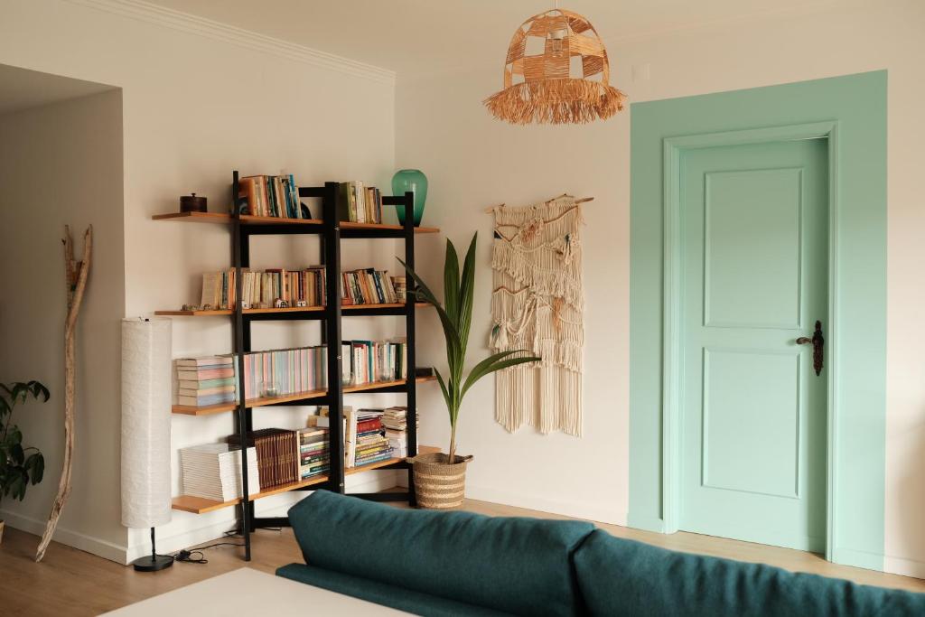 uma sala de estar com um sofá azul e uma estante de livros em Furadouro Cool & Cozy Flat no Furadouro