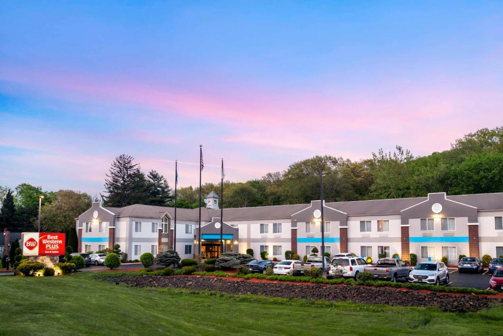 a hotel with cars parked in a parking lot at Best Western Plus New England Inn & Suites in Berlin