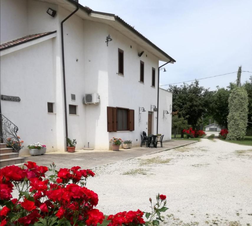 a white building with red flowers in front of it at Agriturismo Il Tratturo in Pescara