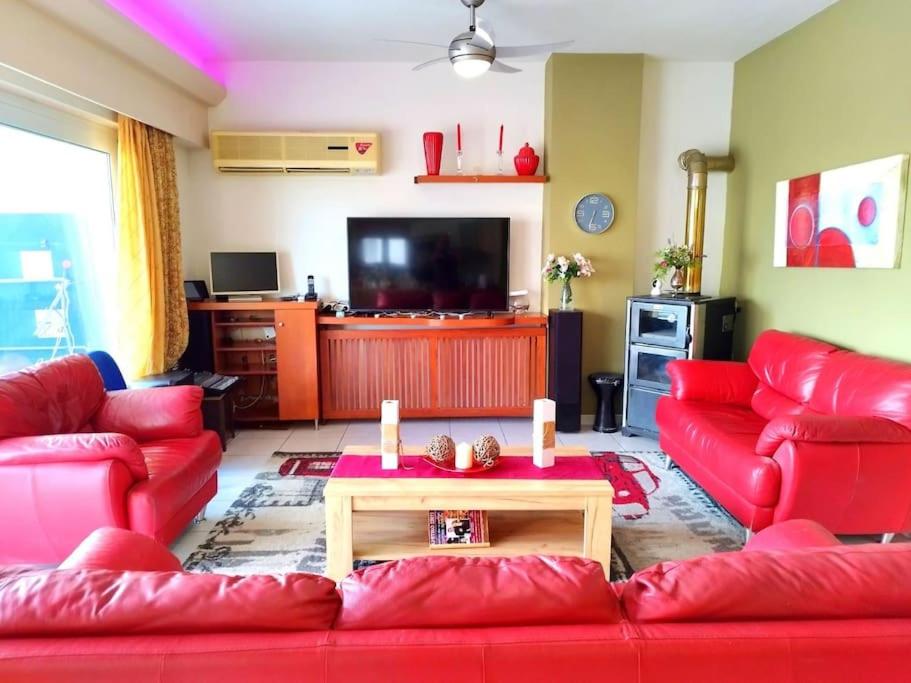 a living room with a red couch and a table at Sunny home crete in Ierápetra