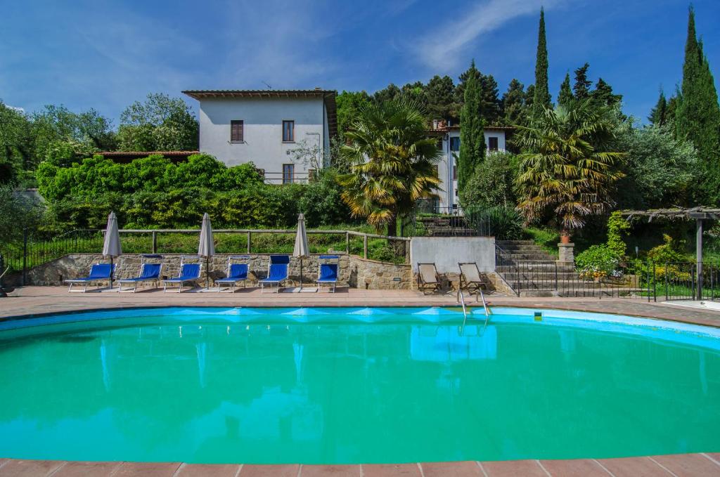 a swimming pool with chairs and a house in the background at Podere"sulle soglie del Bosco" appartament and rooms in Pescia