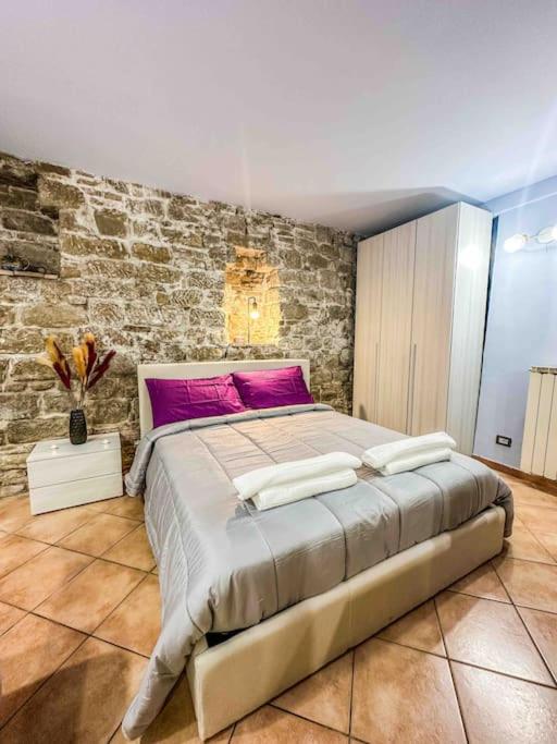 een slaapkamer met een groot bed en een bakstenen muur bij [Centro Storico] La casa di Pietra in Perugia