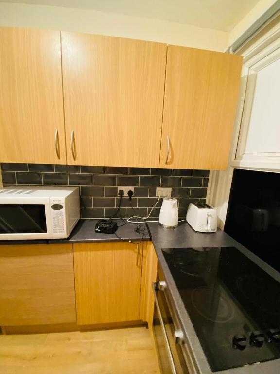 een keuken met houten kasten en een witte magnetron bij Home stay Rooms in Slough