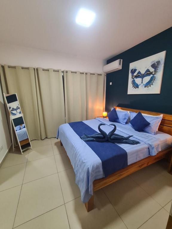 Schlafzimmer mit einem großen Bett mit blauer Bettwäsche und blauen Wänden in der Unterkunft Ocean Blue Villa, Flic-en-Flac in Flic-en-Flac
