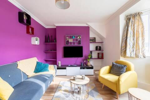 uma sala de estar com paredes roxas e um sofá e cadeiras em cosy 1 bedroom flat near Barking town centre em Barking