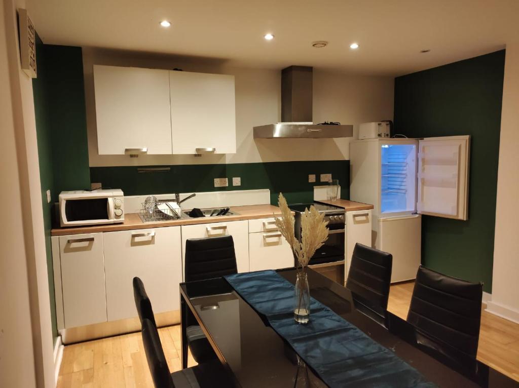a kitchen with a dining table and a kitchen with green walls at EEJs Beautiful 2 bed Apartment - Sheffield centre in Sheffield