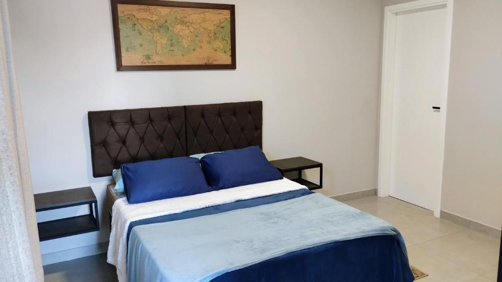 a bedroom with a large bed with blue pillows at Apê Bella Vista Campos in Campos do Jordão