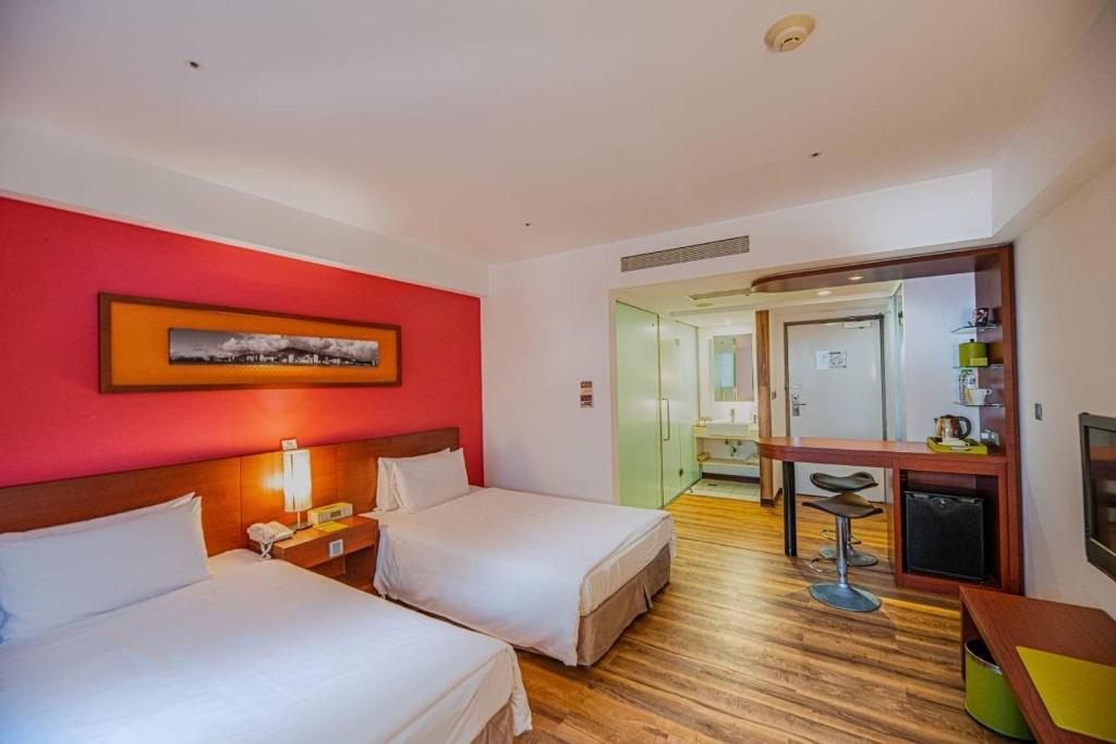 a hotel room with two beds and a desk at Hotel Leisure Tamsui in Tamsui
