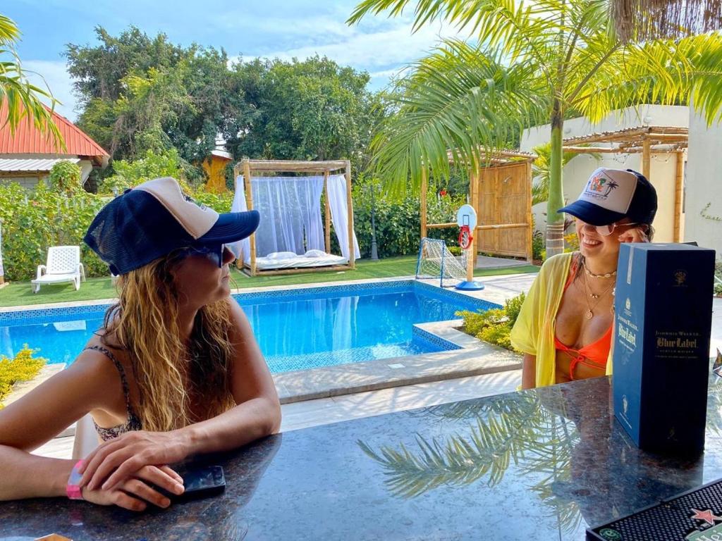 dos mujeres sentadas en una mesa frente a una piscina en Pop House, en Montañita