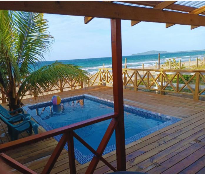 a swimming pool on a deck next to the beach at Villa Devonia - Beachfront Cabins with Pool at Tela, HN in Tela