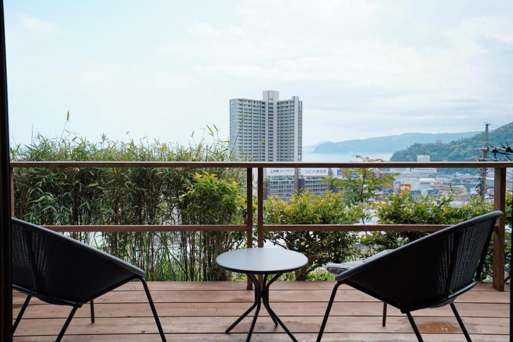 a patio with two chairs and a table on a balcony at new! 熱海桃山邸　Atami terrace villa 〜Sauna & Onsen 〜 in Atami
