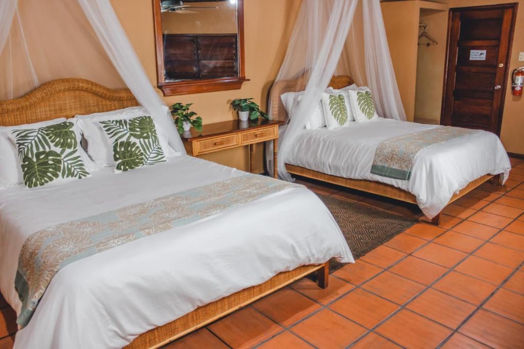 a bedroom with two beds and a tiled floor at The Mayan Garden in Orange Walk