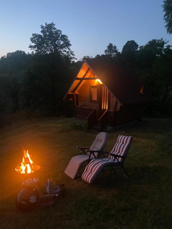 two chairs and a fire in front of a tent at Căbănuță rustică 02 in Băniţa
