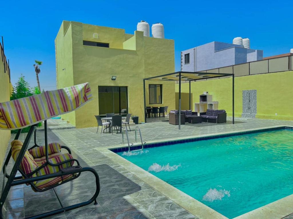a swimming pool with a patio and a house at Al Andalus Chalets ‏ in Shūnat Nimrīn