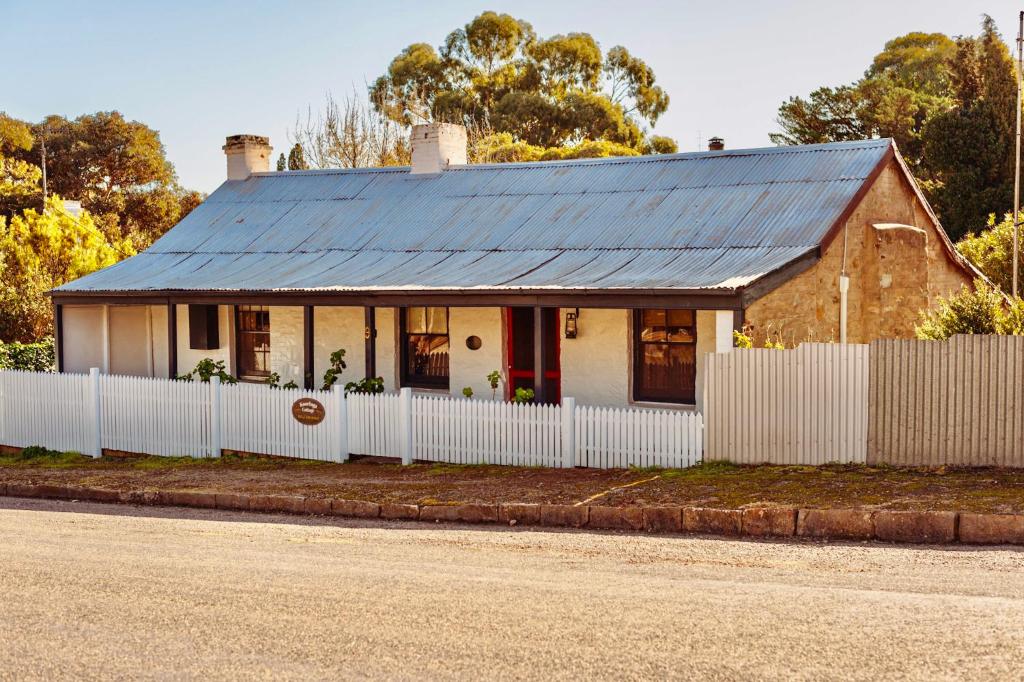 a house with a blue roof and a white fence at Kooringa Cottage in Burra