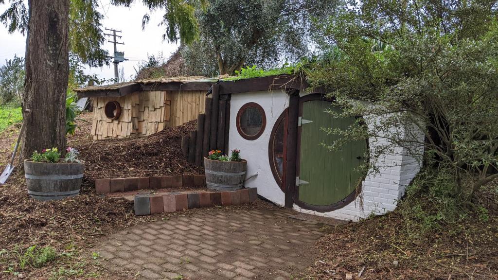 een klein huis met een groene deur in een tuin bij Rivendell Farmstay Hobbit Hole in Cambridge