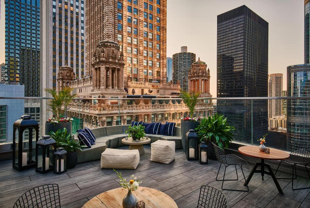 un patio all'ultimo piano con tavoli, sedie e vista sullo skyline della città di Virgin Hotels Chicago a Chicago