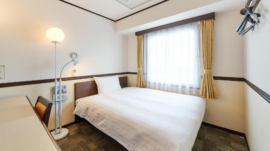 a small room with a bed and a window at Toyoko Inn Osaka Itami Airport in Toyonaka
