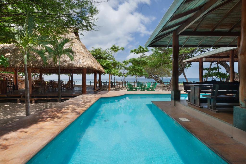 a swimming pool at a resort with a beach at Casa Yosi, Beach Front Piece of Heaven in San Juan del Sur