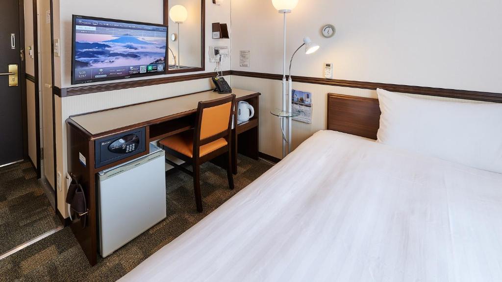 a hotel room with a desk and a bed at Toyoko Inn Osaka Namba Nippombashi in Osaka