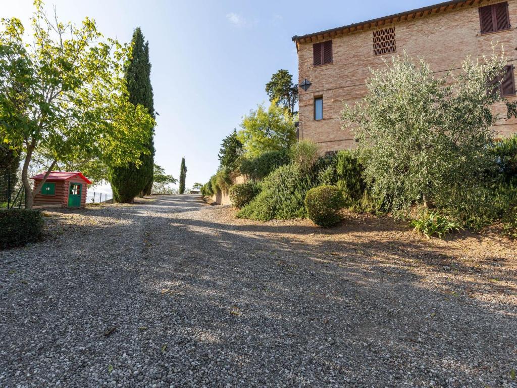 an empty road in front of a brick building at 360 degree view over the Tuscan hills in Buonconvento