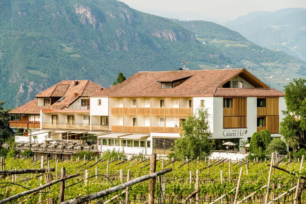 a building on a hill with mountains in the background at Hotel Girlanerhof in Appiano sulla Strada del Vino
