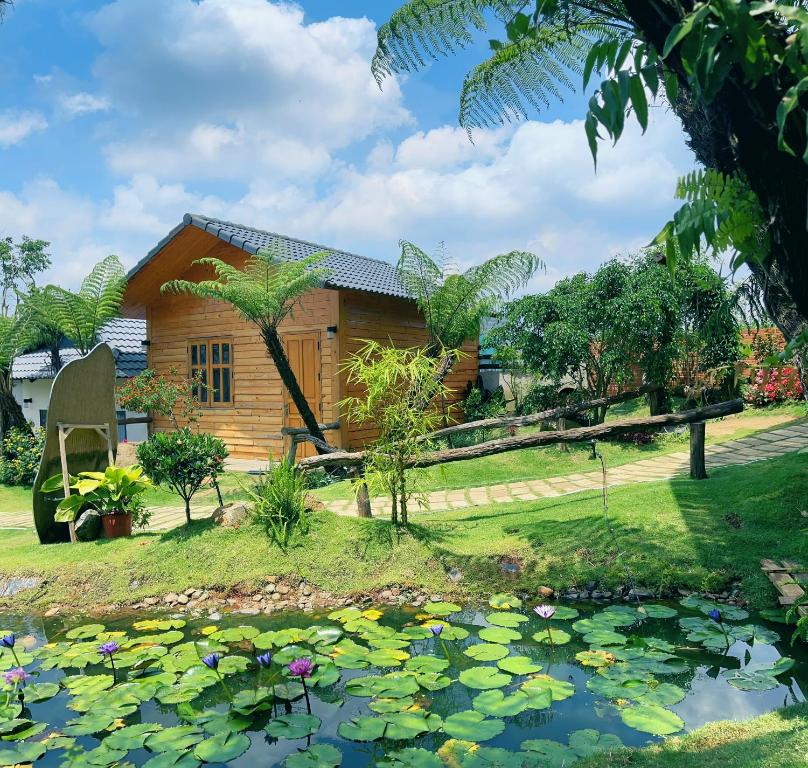 ein Haus mit einem Teich davor in der Unterkunft AN Homestay&coffee in Di Linh