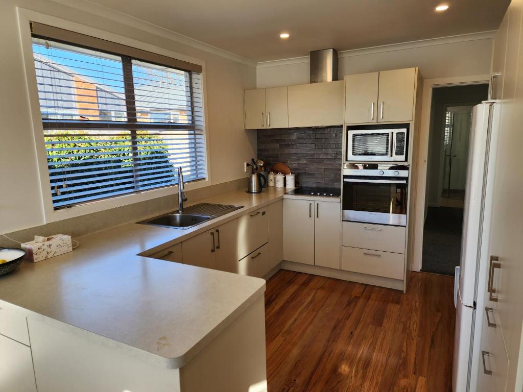 a kitchen with white cabinets and a sink and a microwave at Roslyn Sanctuary Hereford St Dunedin in Dunedin