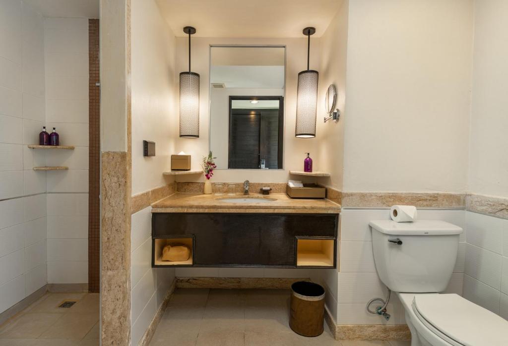 ein Badezimmer mit Waschbecken, Toilette und Spiegel in der Unterkunft Centara Kata Resort Phuket in Kata Beach