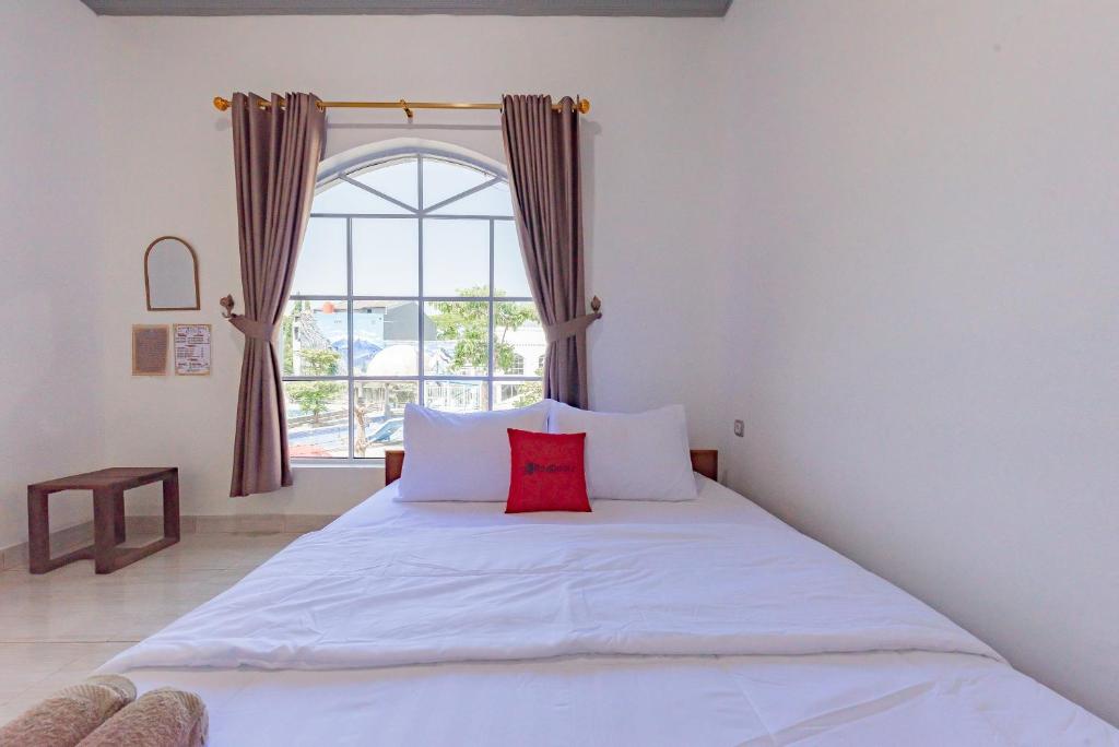 - une chambre avec un grand lit blanc et une fenêtre dans l'établissement RedDoorz @ Niagara Waterpark, à Maracang-tua