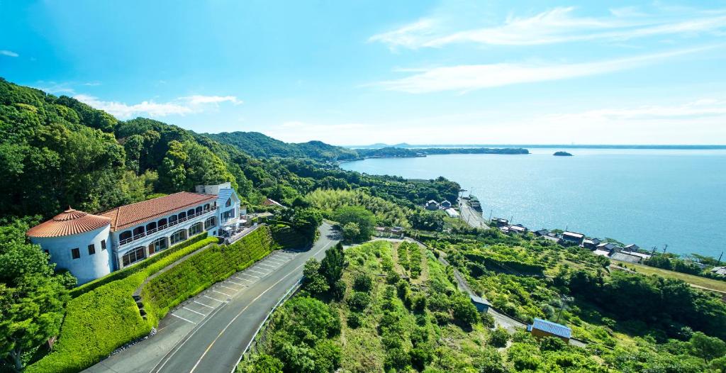 ariale Aussicht auf ein Gebäude auf einem Hügel neben dem Wasser in der Unterkunft 浜名湖オーベルジュ　キャトルセゾン in Ōsaki