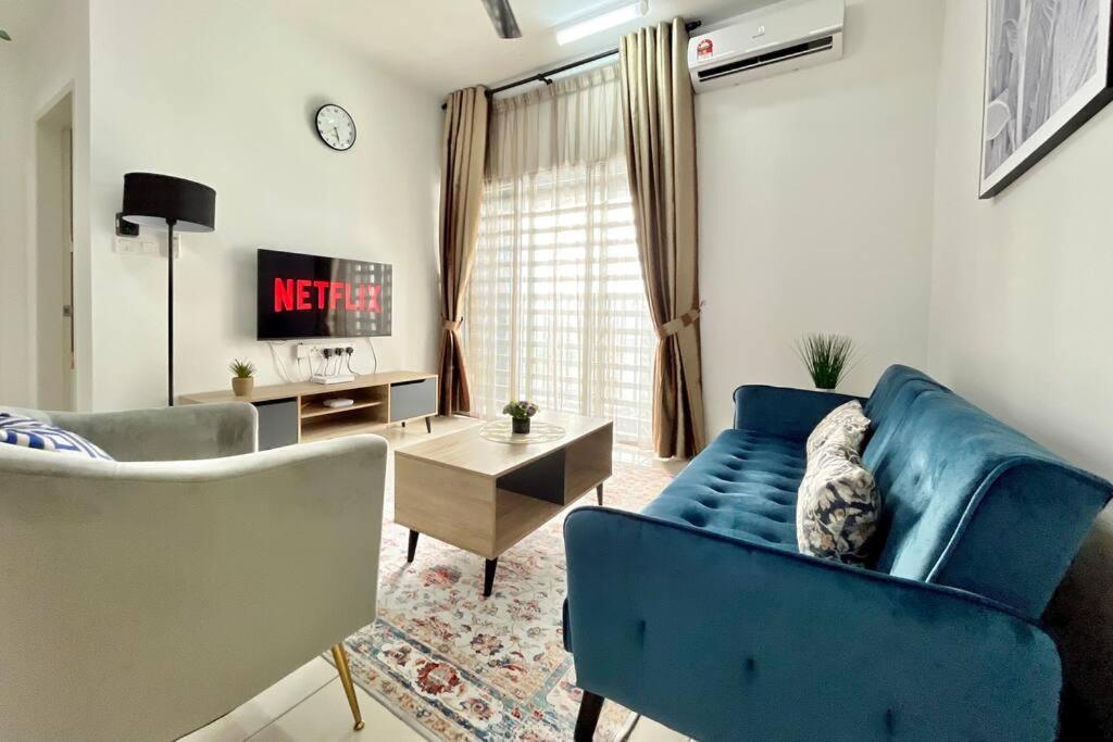 een woonkamer met een blauwe bank en een tafel bij 2BR Alanis Suite With Balcony in Sepang