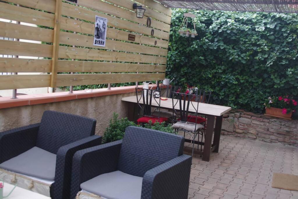 d'une terrasse avec des chaises, une table et une clôture. dans l'établissement Gite la tuilerie, à Thuir