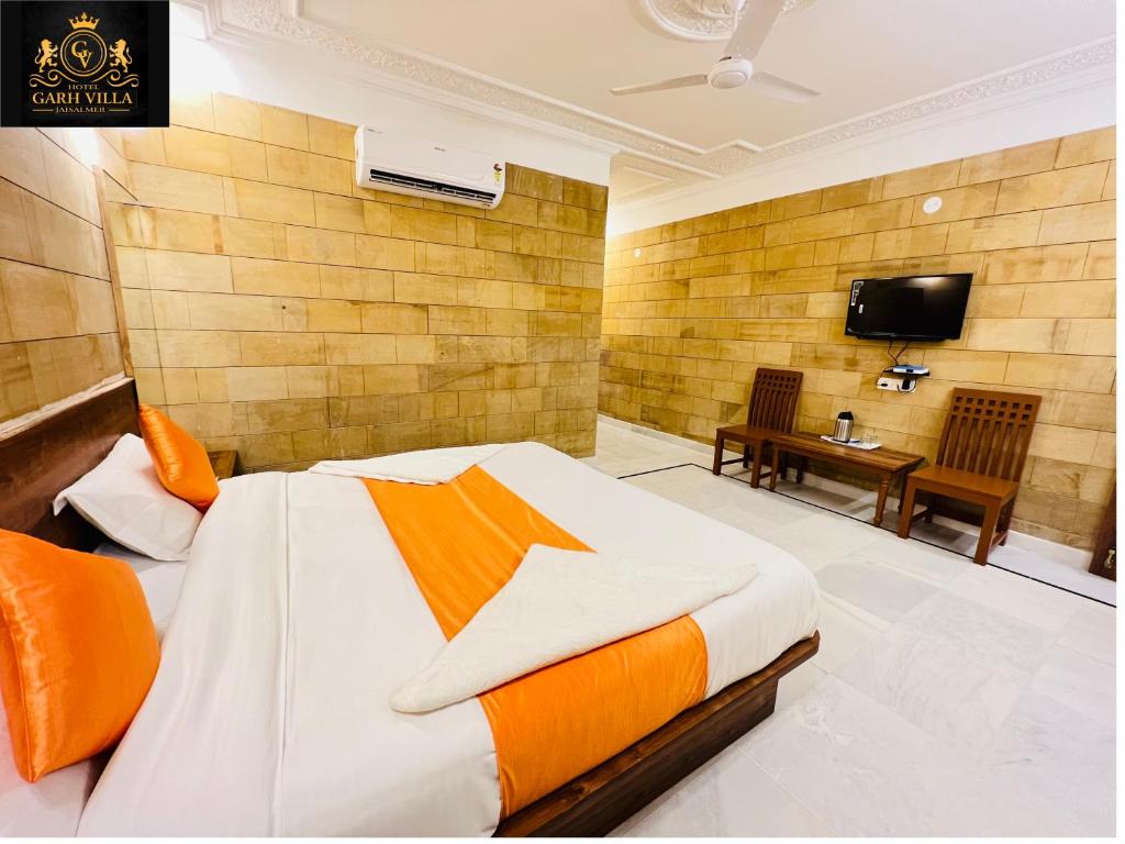 ein Schlafzimmer mit einem Bett und einem TV an der Wand in der Unterkunft Hotel Garh Vila in Jaisalmer