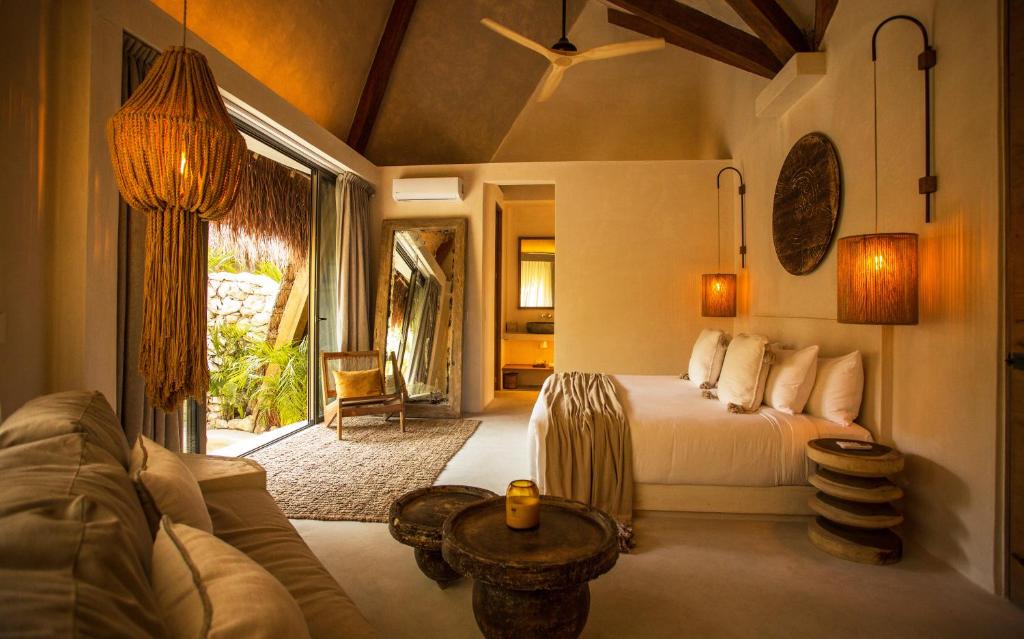 a bedroom with a bed and a couch at Hotel Muaré Tulum Wellness and Spa in Tulum